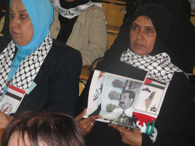 عراقية صامتة تحتضن صورة صدام حسين والدموع في عينيها